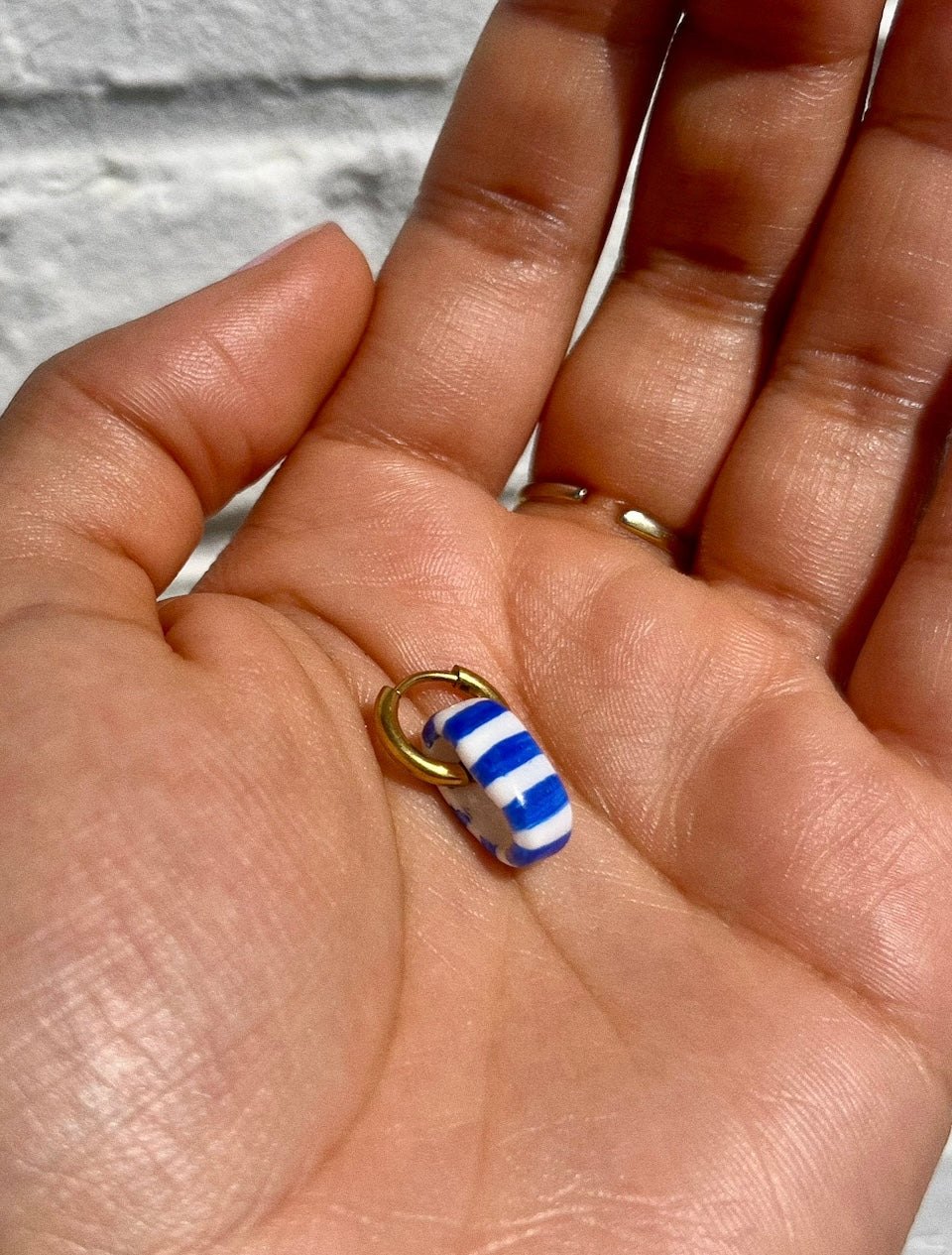 Main tenant boucle d'oreille en forme de bouée couleur marinière